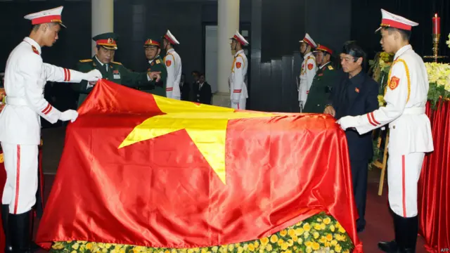 越南士兵在武元甲大將的靈柩上覆蓋國旗，他的長子武奠邊（右二）在靈柩旁守候。