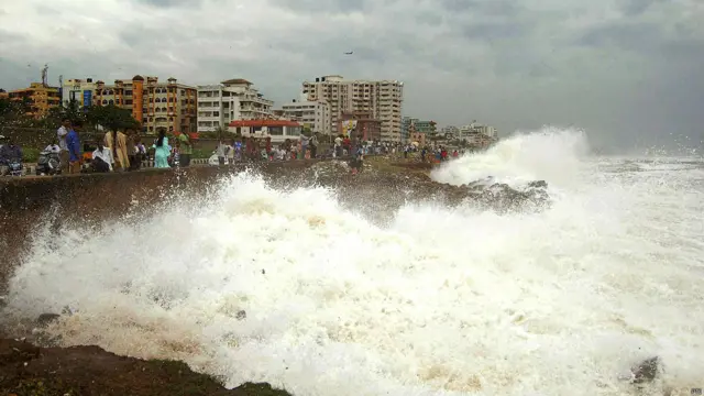 शनिवार को विशाखापत्तनम में बंगाल की खाड़ी के तट पर ऊंची लहरे देखते लोग.