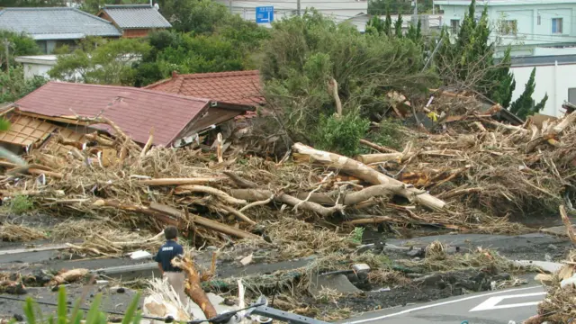 日本伊豆大岛大岛町一名男子站在遭泥石流摧毁的民房废墟（16/10/2013）