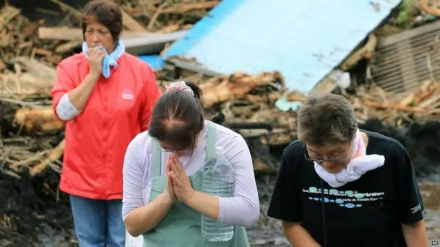 泥石流幸存者向被抬出的死者遗体默哀（16/10/2013）