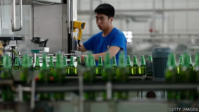 یک کارگر کارخانه آبجوسازی بطری های آبجو را در خط تولید آبجو در فوجین چین کنترل می کند.