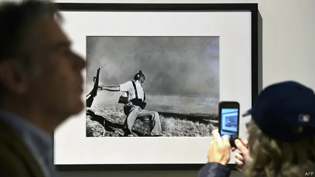 یک بازدیدکننده از عکس های رابرت کاپا در موزه ای در رم، آوریل ۲۰۱۳، از 'سرباز تیرخورده' عکس می گیرد