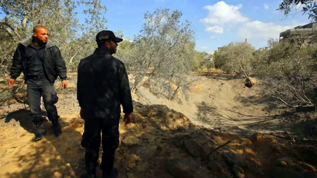 عنصران تابعان لقوات الامن الفلسطينية يتفقدان موقع القصف الاسرائيلي