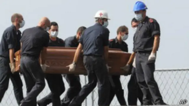 Equipe médica transporta caixão de vítimas (foto: AP)