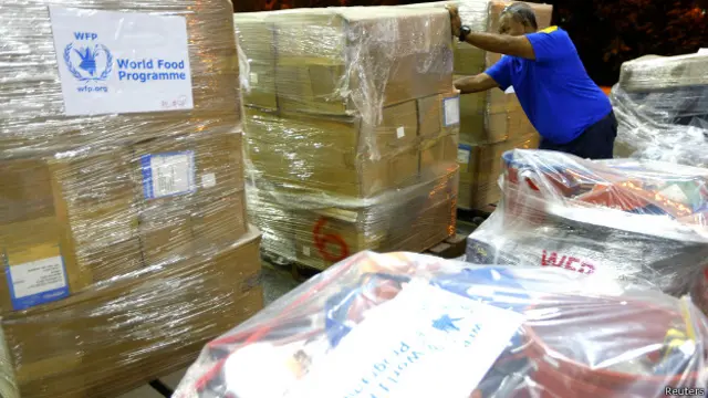یک کارگر کمک های برنامه جهانی غذا را که عازم فیلیپین است جابجا می کند