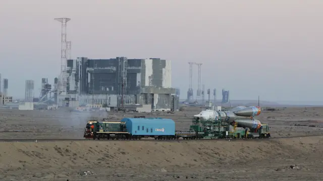 Непосредственная подготовка к старту ракеты с олимпийским факелом началась за два дня до него, 5 ноября. Ракету "Союз" вывезли на специальном поезде из огромного ангара - монтажно-испытательного корпуса. Путь до стартовой площадки занял около двух часов. Дорога пролегает рядом с полуразрушенным корпусом, где четверть века назад готовилась к старту ракета "Энергия". Справа видны конструкции стартового комплекса, с которого "Энергия" взлетала с кораблем "Буран". Репортаж побывавшего на Байконуре корреспондента Би-би-си Павла Аксенова.