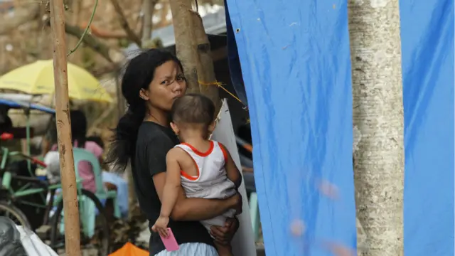 Tayfundan sağ kurtulan ve çocuğuyla birlikte çadır kampa sığınan bir kadın.