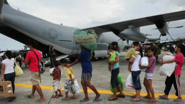 مردم برای سوار شدن به یک فروند هواپیمای C-130 ارتش آمریکا که کمک‌های ارسالی را به فرودگاه تاکلوبان آورده صف بسته‌اند تا به مانیل پایتخت منتقل شوند.