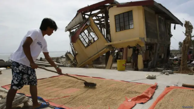 کشاورزی در شهرک هرنانی در استان سامار در مقابل خانه ویرانش برنج باد می‌دهد. دو جزیره سامار و لیته بیشترین آسیب را در این توفان دیدند.