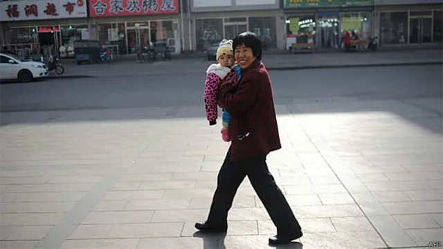 Mulher caminha na rua com um bebê no norte da China (AFP/Getty)