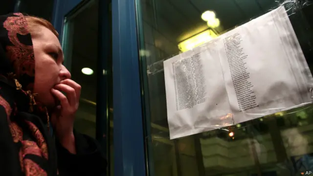 مسافروں کے لواحقین ہوائی اڈے کے باہر آویزاں ایک فہرست پر اپنے پیاروں کے نام تلاش کر رہے ہیں