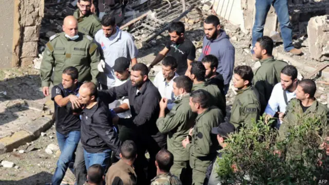 انفجار در برابر سفارتخانه ایران در بیروت به کشته شدن بیش از بیست نفر منجر شده است. در عکس ماموران ایرانی و لبنانی در حال بردن یک مظنون به دست داشتن در انفجار دیده می شوند.