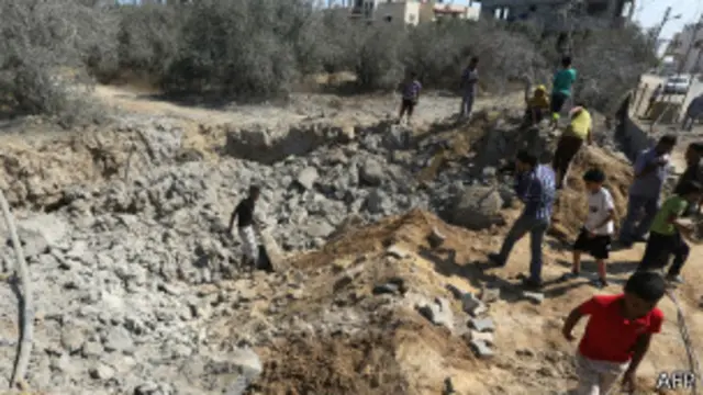 صورة أرشيفية لفلسطينيين يفحصون موقع غارة إسرائيلية في قطاع غزة