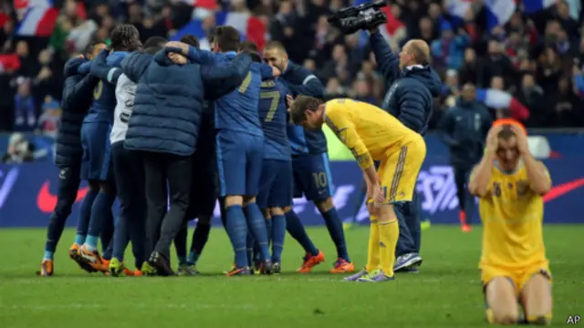 Seorang pemain Ukraina tertunduk lesuh dengan latar para pemain Prancis.