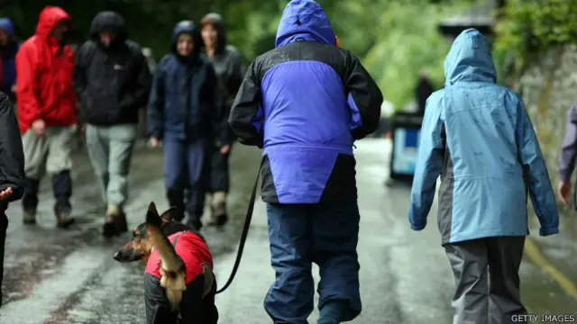 Pessoas com capas de chuva. Foto: Getty Images