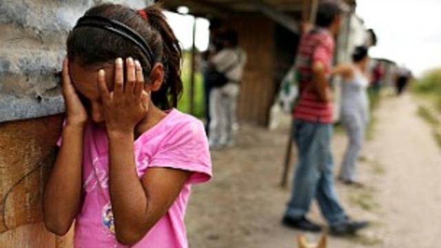 Una niña hondureña llora mientras su casa es desmantelada en un barrio de invasión.