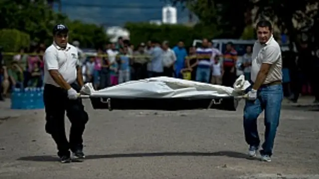 Funcionarios judiciales cargan un cadáver.