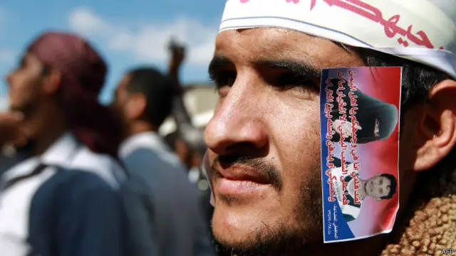 Homem protesta com foto Huda e Arafat, em Sanaa (AFP)