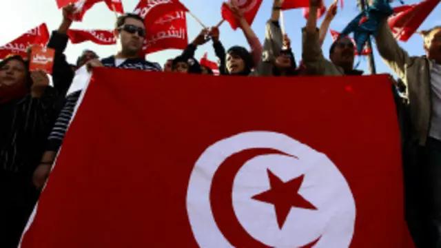 Des manifestants exhibent le drapeau national, en novembre 2013 à Tunis 