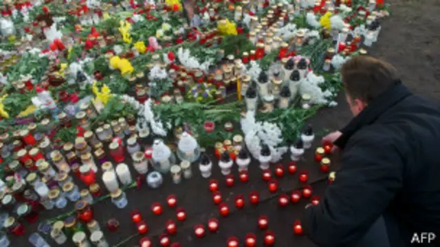 Мужчина зажигает свечу во время минуты молчания на месте трагедии в Латвии 