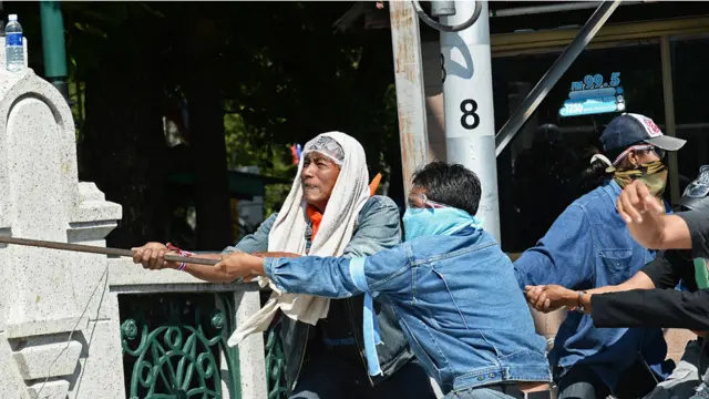 مظاہرین رکاوٹ کے طور پر رکھے جانے والے سیمنٹ کے بلاک ہٹانے کی کوشش کر رہے ہیں۔ 