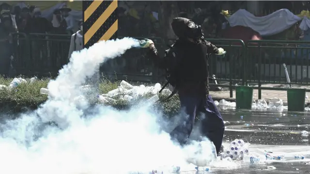 ایک شخص آنسو گیس کا شیل واپس سکیورٹی فورسز کی جانب پھینک رہا ہے۔ 