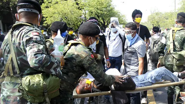 एक घायल प्रदर्शनकारी को अस्पताल ले जाते अधिकारी