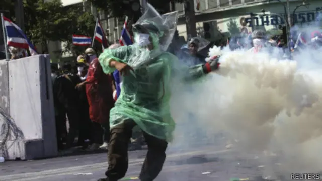 曼谷街头一名示威者把催泪瓦斯罐扔回警察阵地(2/12/2013)