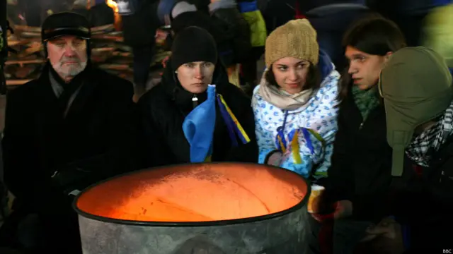 Рядом люди греются у бочек, в которых разведены дровяные костры, поэтому эта часть Майдана окутана ароматным дымом.