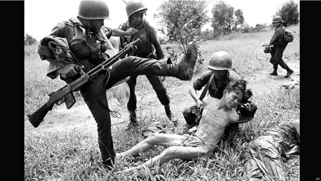 جنوبی ویتنامی فوجی ایک شخص کو لات سے مار رہا ہے جس پر شک ہے کہ وہ ویت کونگ کا مخبر ہے۔ 