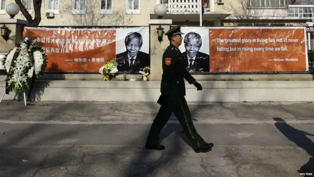 南非大使馆外一名武警在悼念曼德拉的横幅前走过（6/12/2013）