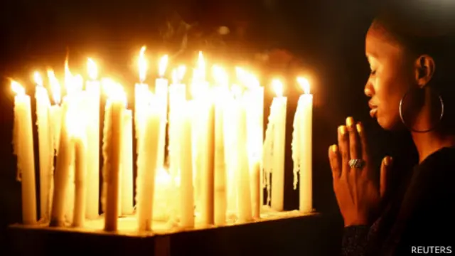 一名南非女子在约翰内斯堡曼德拉故居外架设的烛台前祷告(7/12/2013)