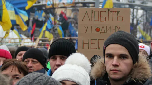 Подавляющее большинство плакатов и транспарантов - самодельные, как вот этот кусок картона с цитатой из стихотворения Владимира Сосюры : "Любите [Украину] в час ненастья"