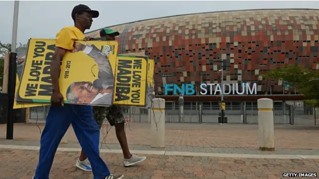 अफ्रीकन नेशनल कांग्रेस के कार्यकर्ता स्टेडियम के बाहर पोस्टर लगा रहे हैं.