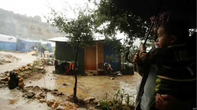 بدأت مفوضية الأمم المتحدة لشؤون اللاجئين برنامجها لفصل الشتاء بنقل المساعدات والمسلتزمات الشتوية على متن طائرات من العراق إلى مخيمات اللاجئيين خارج سوريا، وبعض المناطق بداخلها إن لم يتعذر الوصول إليها. الصورة لأب وابنه يحتميان من الأمطار في مخيم بقرية كترمايا اللبنانية. 