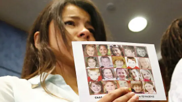 सैंडी हुक स्कूल में मारे गए बच्चों की तस्वीर दिखाती लड़की