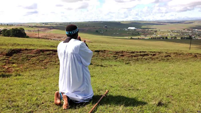 ایک پادری منڈیلا کے گھر کی جانب رخ کر کے دعا کر رہا ہے۔ ان کے خاندان کے افراد اور قبیلے کے بہت سے اراکین گذشتہ شب عبادت میں مصروف رہے اور روایتی انداز میں ان کی زندگی کے اہم واقعات کے بارے میں تعریفی گیت گاتے رہے۔