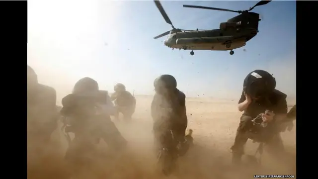 صحفيون يحتمون من الغبار المتصاعد أثناء إقلاع طائرة مروحية في قاعدة بريطانية في افغانستان، حيث كان رئيس الوزراء البريطاني دايفيد كاميرون في زيارة لتفقد أوضاع الجنود.