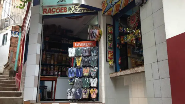 A expulsão dos traficantes beneficiou os comerciantes locais. Mais de 51% já estão formalizados. Lúcia Barros vive há 57 anos no morro, 18 deles à frente de uma pequena loja que vende de pipas a brinquedos e animais de estimação. PA Associação de Moradores fica logo no início do morro, onde as vielas contam com iluminação pública instalada após a pacificação. (Foto: Jefferson Puff/BBC).