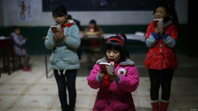 Murid-murid sekolah dasar membaca dari Buku Kecil Merah