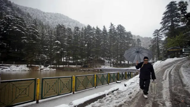 ہماچل پردیش کے شہر دھرم شالہ میں چھاتے کے سہارے خود کو برفباری سے بچانے کی کوشش میں ایک تبتی پناہ گزین۔