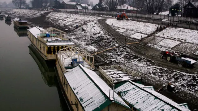 یہ دریائے جہلم کا کنارہ ہے۔ دریا میں کھڑی ہاؤس بوٹ کی چھت پر برف جمع ہو گئی ہے۔ کشمیر میں موسم کی پہلی برف پڑی ہے۔