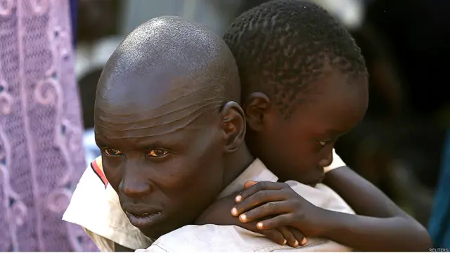 Hombre con su hijo en brazos en un refugio de la ONU en Yuba