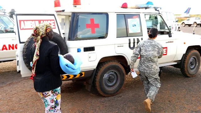 La madre con su bebé herido, provenientes de Bor, corren hacia una ambulancia de la ONU