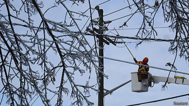 Un trabajador trata de quitarle el hielo a un cable