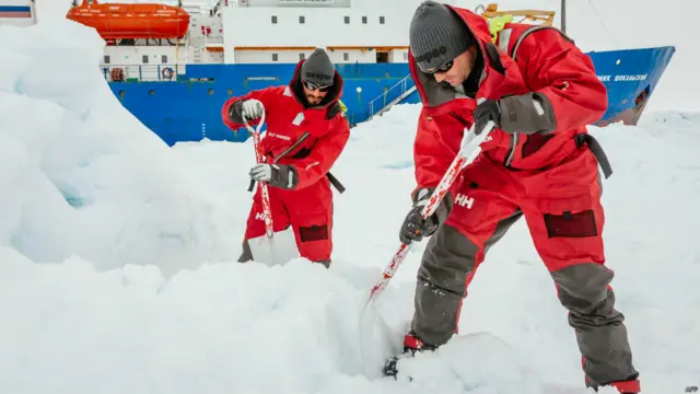 Dua orang ilmuwan tengah menyiapkan landasan helikopter, Andrew Peacock / www.footloosefotography.com/AFP