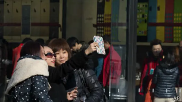 中国人在苹果手机店门前用其它品牌手机拍照。