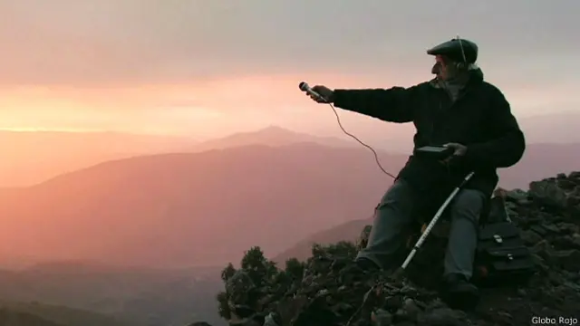 Anciano en la montaña con un micrófono