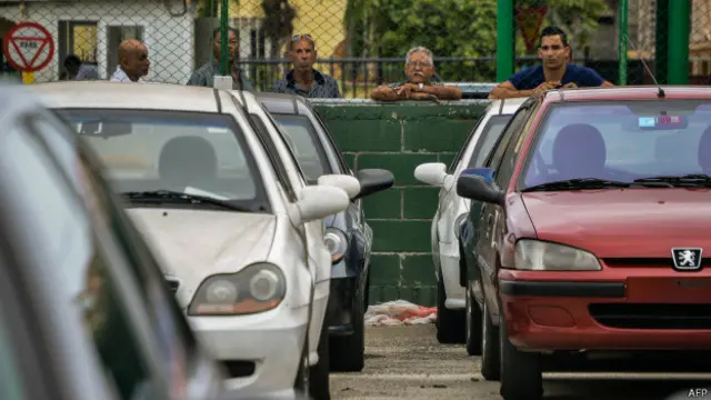 Cubanos en La Habana miran coches nuevos y usados en un concesionario