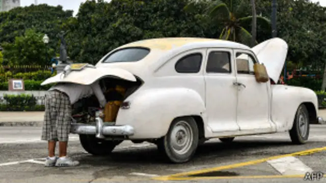 Hombre intenta reparar su viejo coche en La Habana